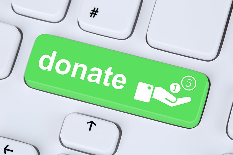 A white computer keyboard with the word 'donate' on a green key