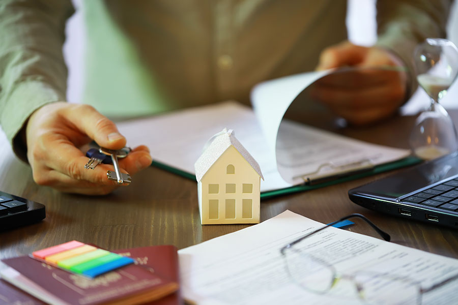 Real Estate Agent Reviewing Documents with Model House, Contract, and Key