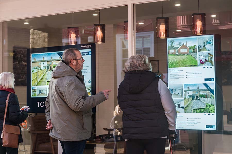 A group of people looking in the window of an estate agent