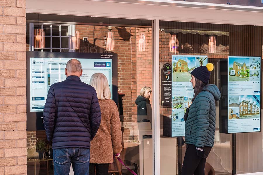 three people looking in an estate agent window