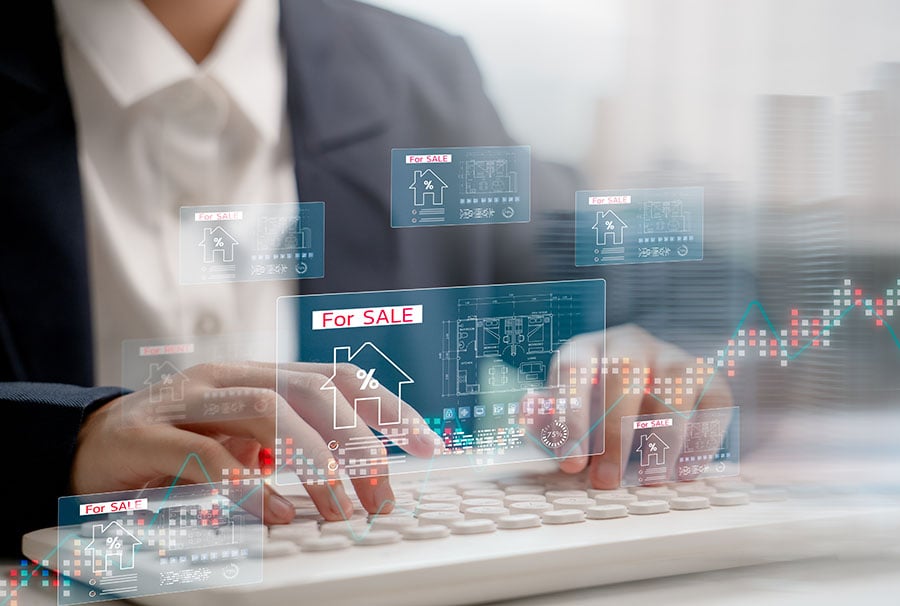 A close-up of hands typing on a keyboard, overlaid with a graphic of houses and graphs