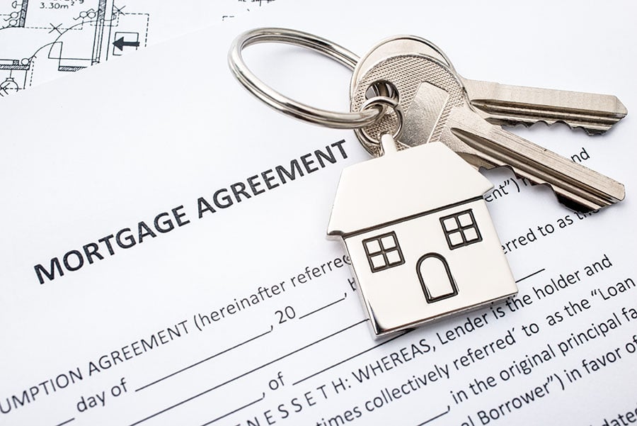 a keyring with a house on it on top of a mortgage agreement