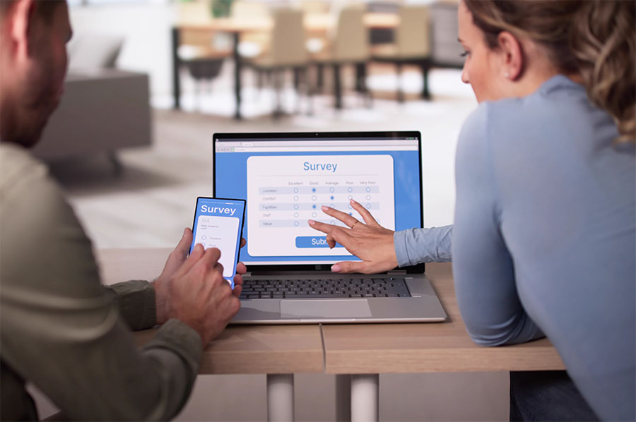 Two people look at a survey on an open laptop