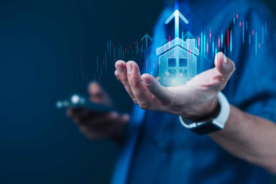A computer generated house, with upward arrows coming from its roof, sits on a man's hand