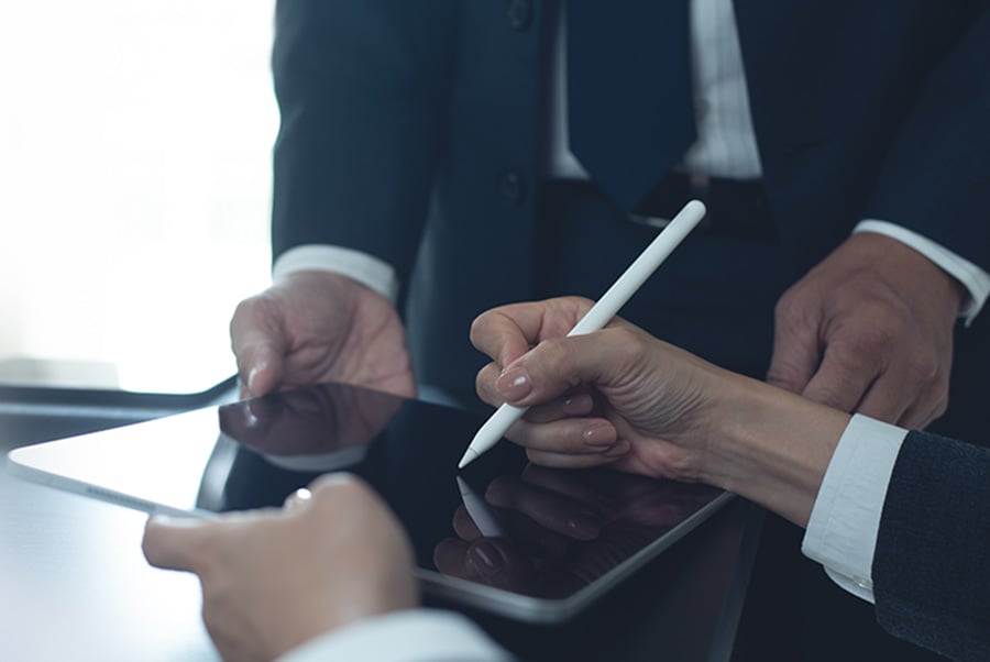 A close-up of hands holding a tablet with one of the people holding a special pen to sign the screen
