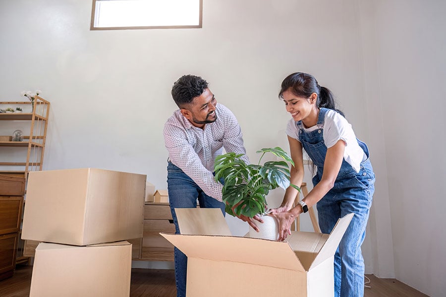 A couple smiling as they unpack boxes in an empty room