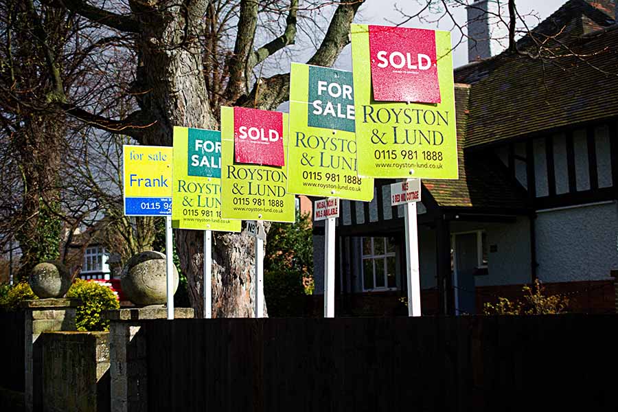 A row of for sale and sold signs outside houses