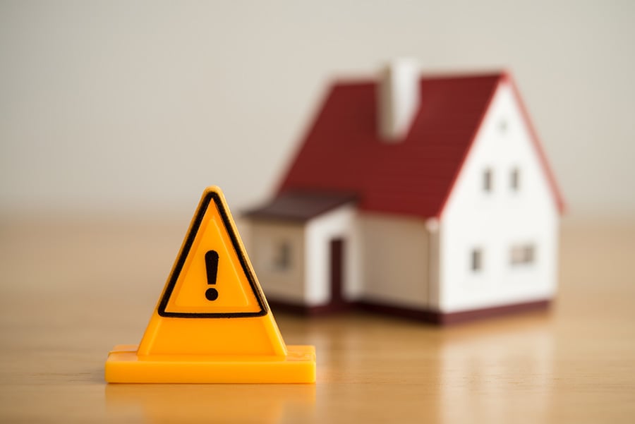 A model house with a yellow sign in front of it with an exclamation mark
