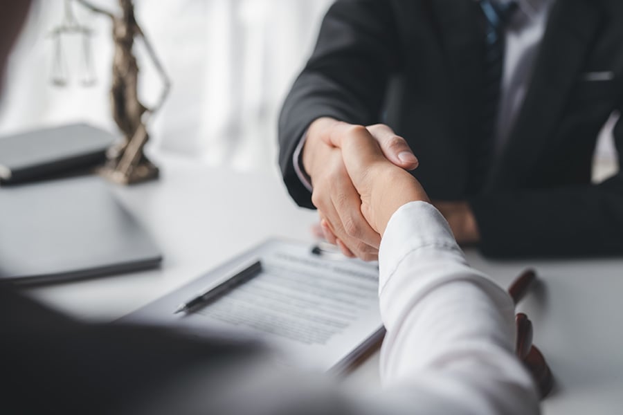 Close-up of a solicitor shaking hands with a client over a desk