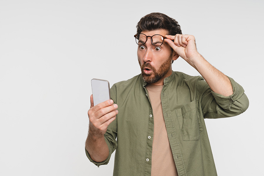 A shocked man looking at the phone in his hand
