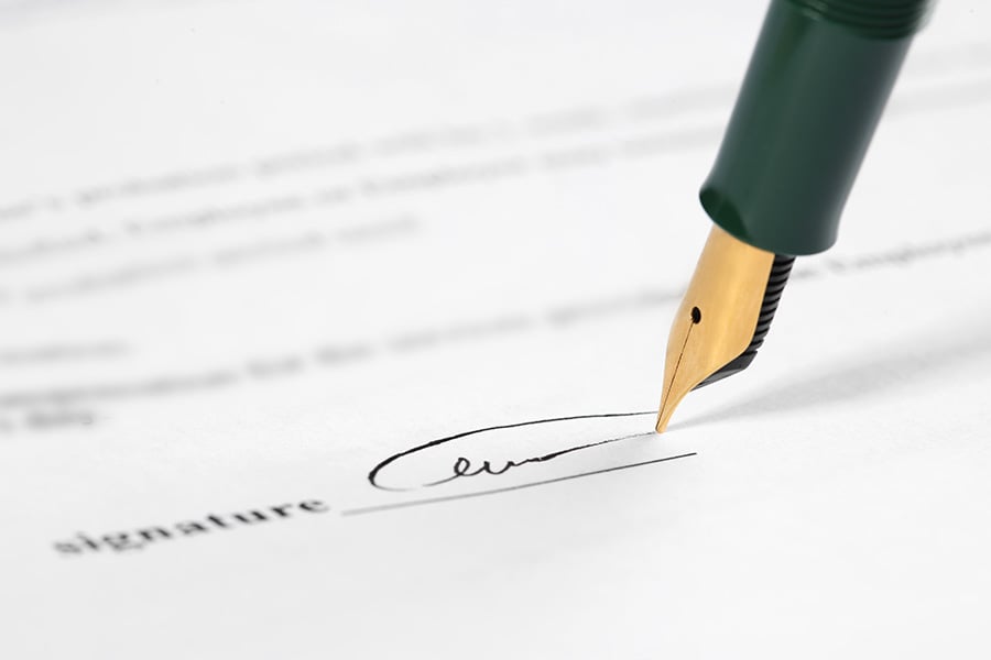 A close-up of a traditional fountain pen being used to sign a document