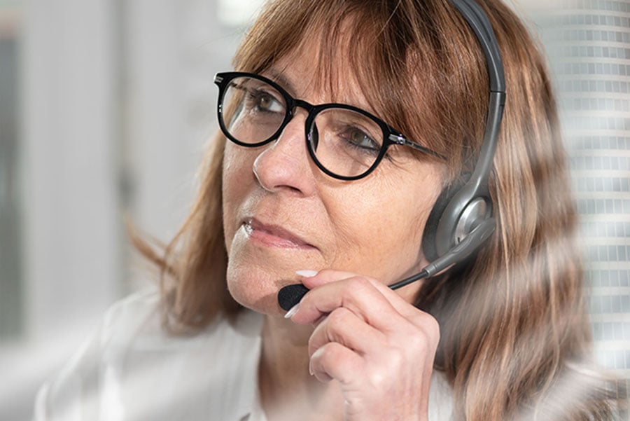 A kind-looking woman wearing a phone headset
