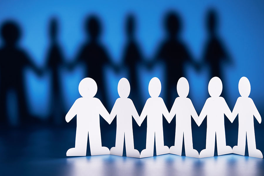 A row of white paper figures, casting a shadow of dark figures