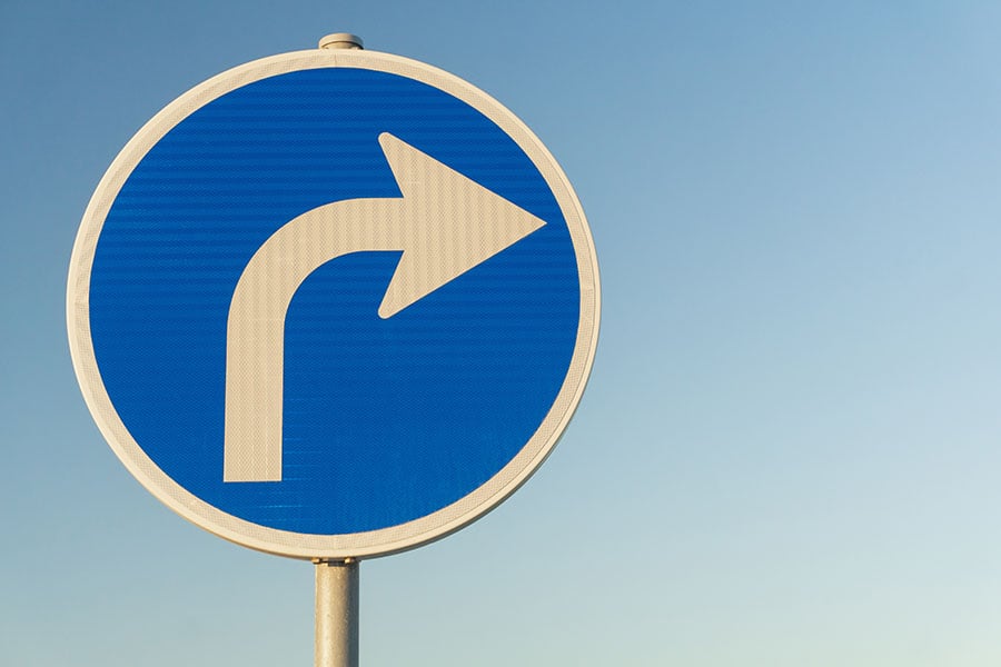 A blue road sign with a white arrow pointing right
