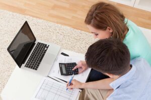 A millennial couple using a calculator to work out a budget