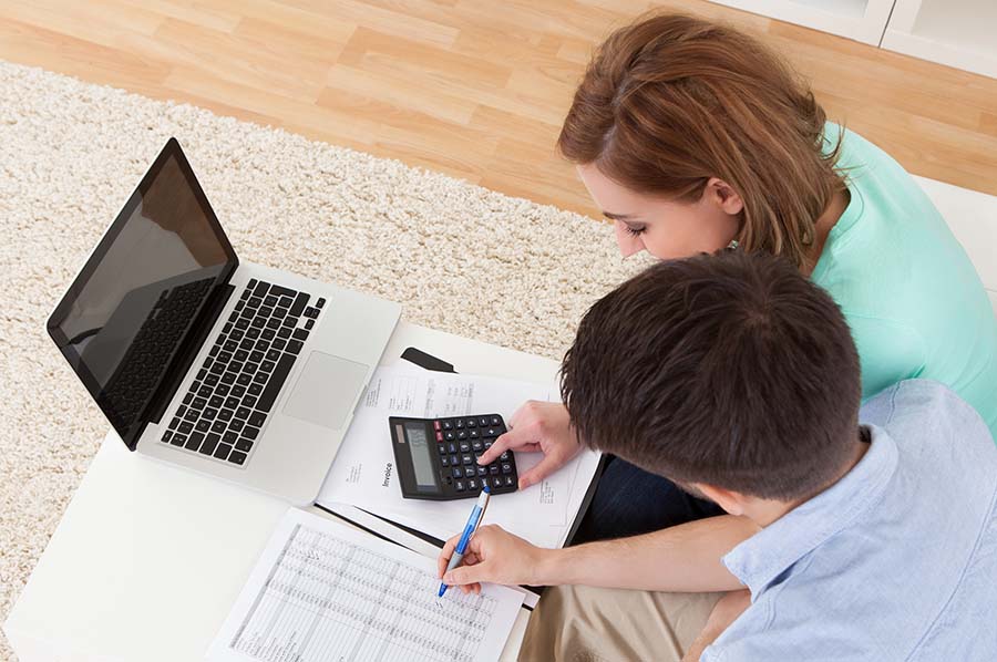 A millennial couple using a calculator to work out a budget