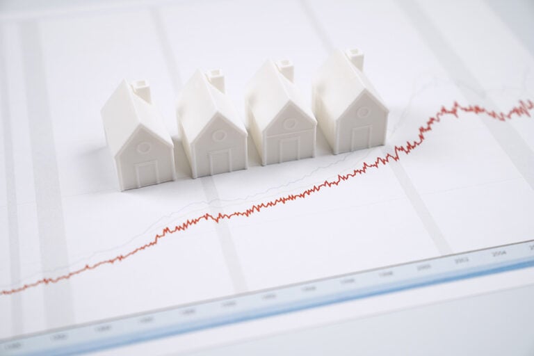 Four small white houses placed on a graph of a red line in a slight upwards trajectory