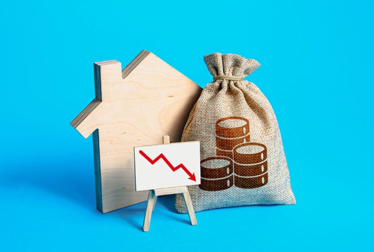 A small wooden house, a sack with a coin on the front and a graph with a downward-pointing arrow