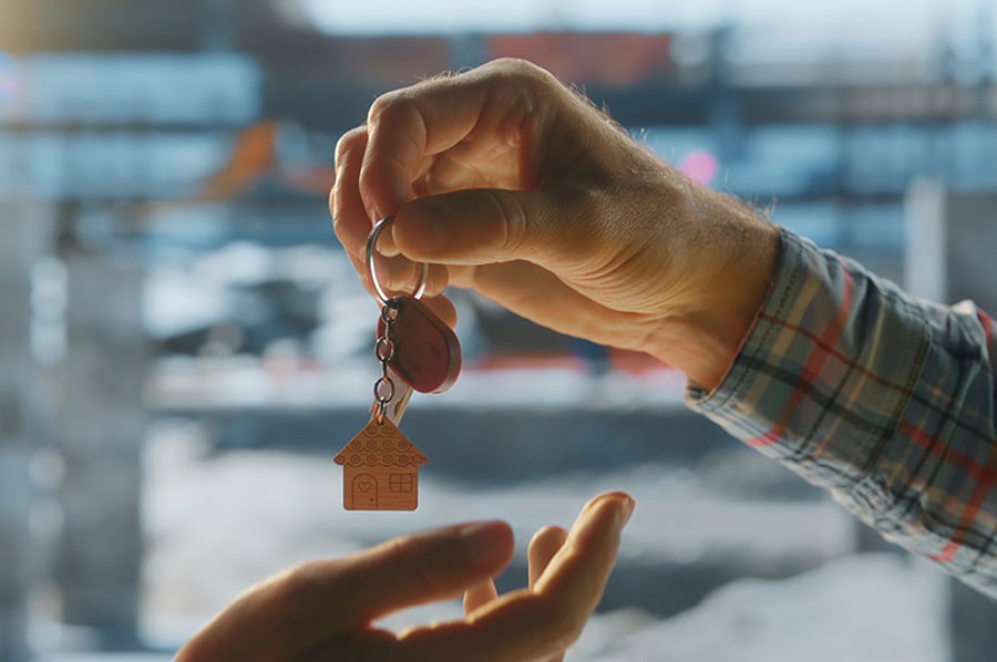 A close-up of a house key being passed from one hand to another