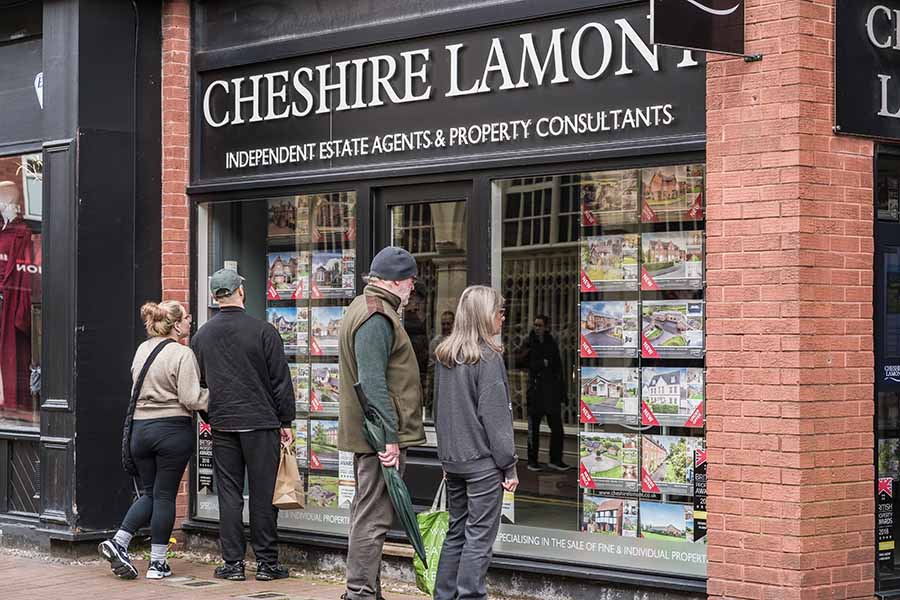 Four people looking in an estate agents' window