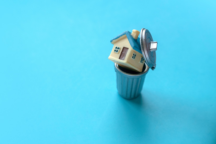 A small toy house is discarded in a rubbish bin