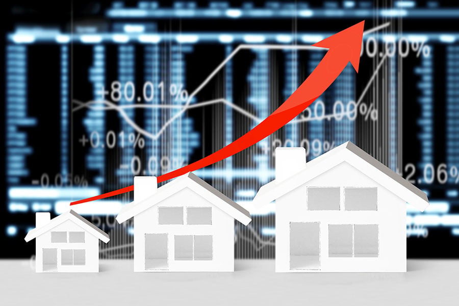 A graphic of three white houses in front of a financial graph, with a red arrow pointing upwards