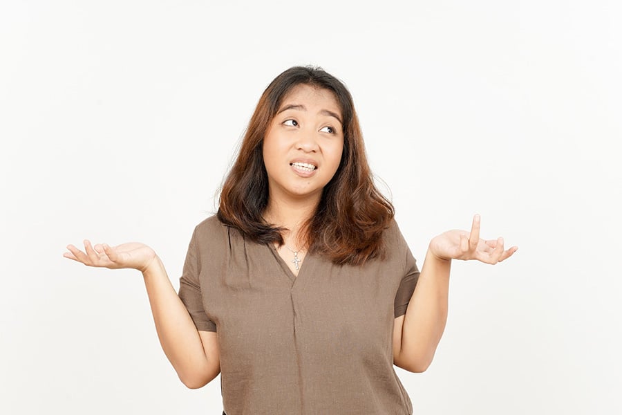 A young woman shrugs her shoulders and looks dismissive
