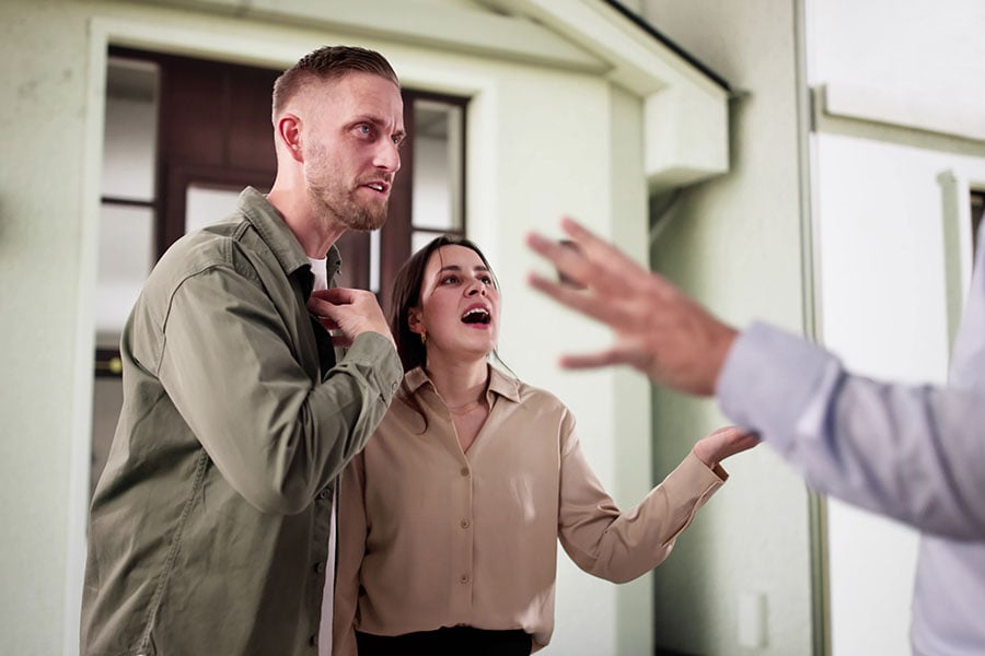 An angry looking couple argue with a man just out of frame