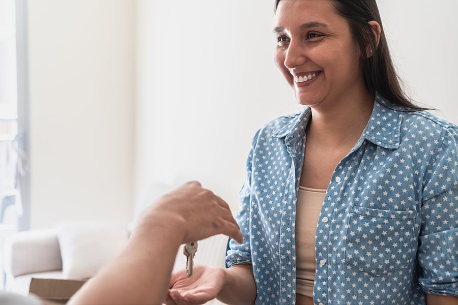A happy looking woman is handed a set of house keys