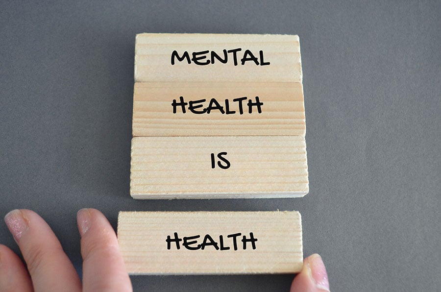 The words 'mental health is health' written on wooden blocks