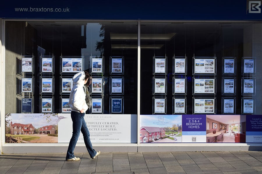 A person walking past an estate agent window