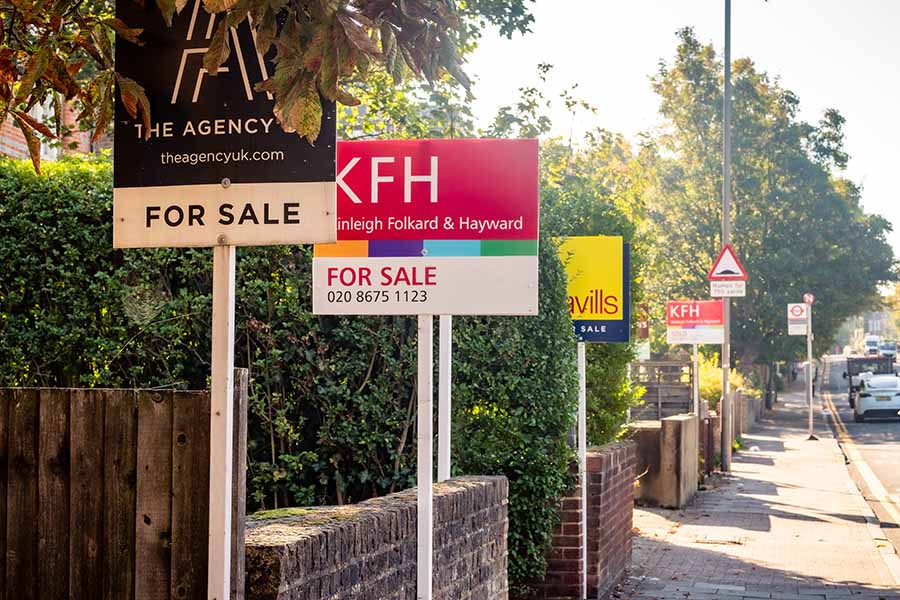 A row of for sale signs outside houses on a street in London