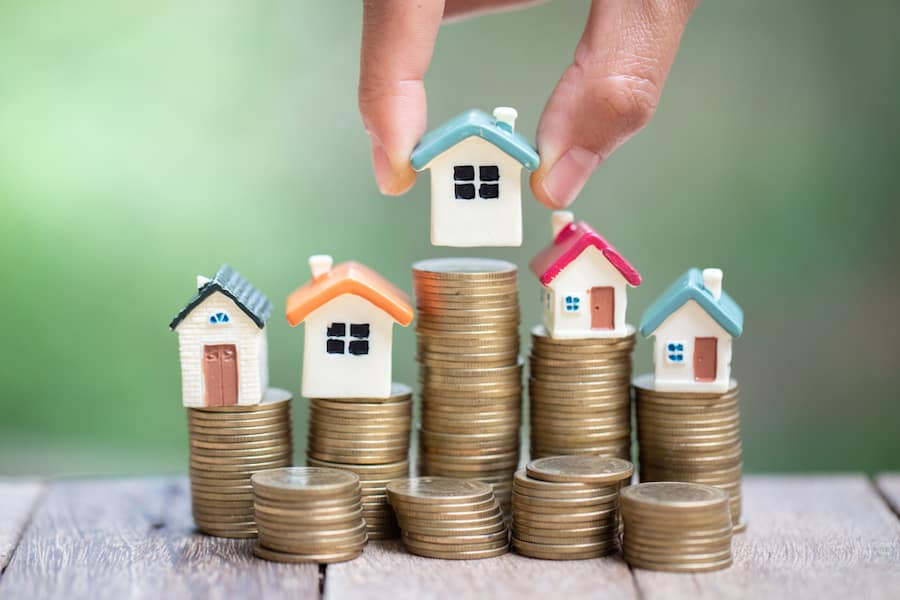 Investor show hand holding a model home and coin