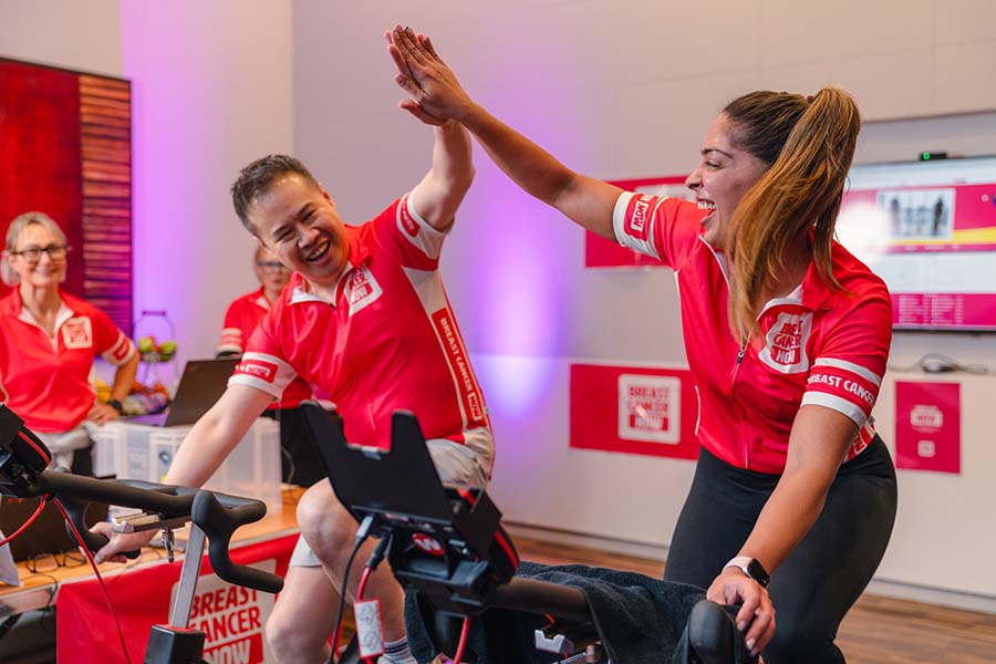 A man and a woman high five each other while on exercise bikes