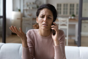 A frustrated-looking woman makes a complaint over the phone