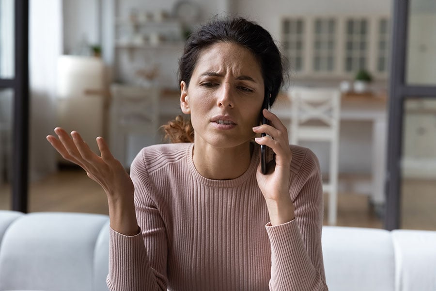 A frustrated-looking woman makes a complaint over the phone