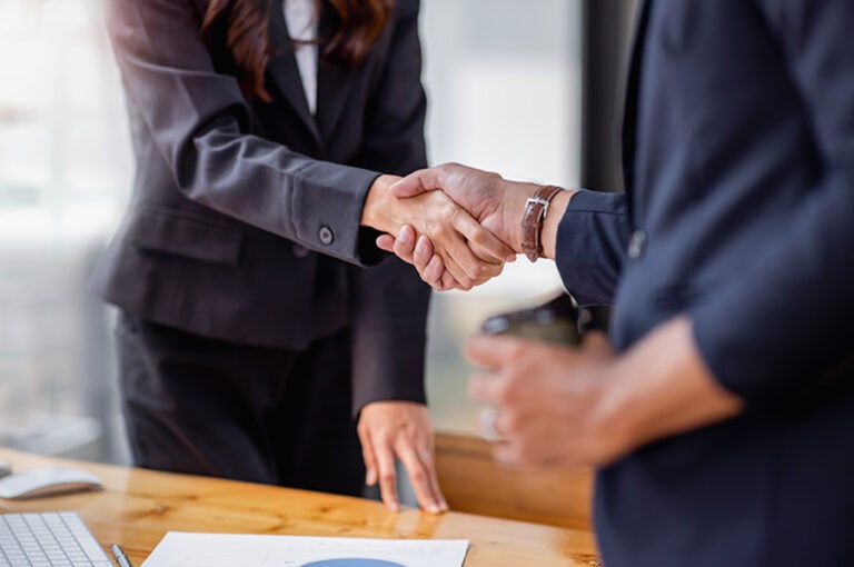 Close-up of business professionals in black suits shaking hands over a business deal