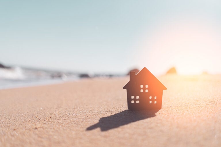 A small wooden house in sand on a beach in direct sun