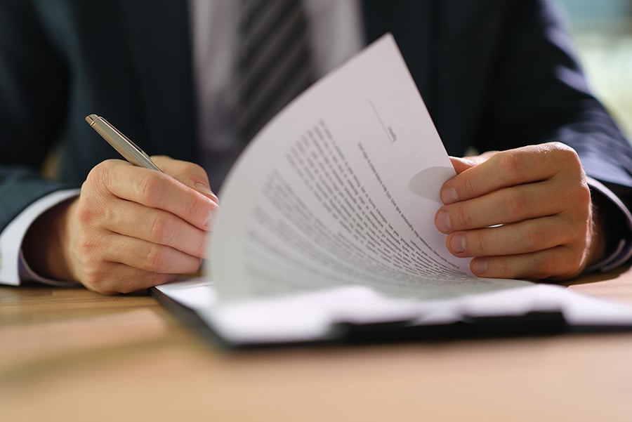 A man in a dark suit signing insurance papers