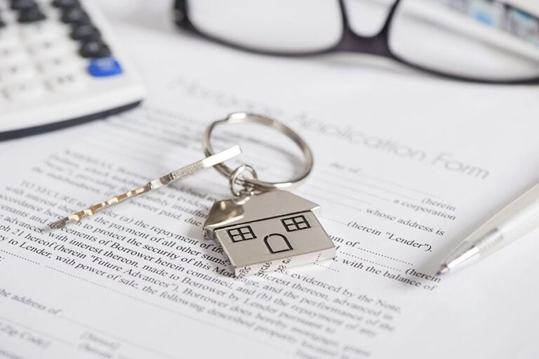 A house-shaped keyring on top of a mortgage application form and next to calculator