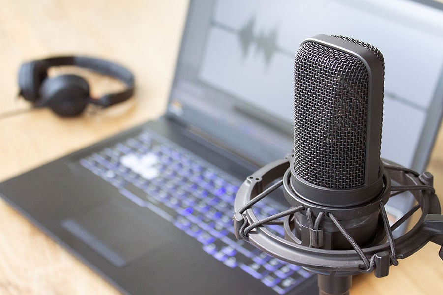 A laptop and professional microphone set up for recording a podcast