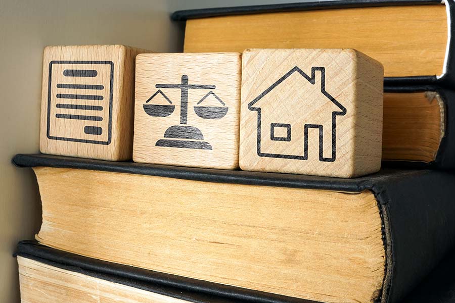 Small wooden cubes printed with a house, scales and a document on top of old books