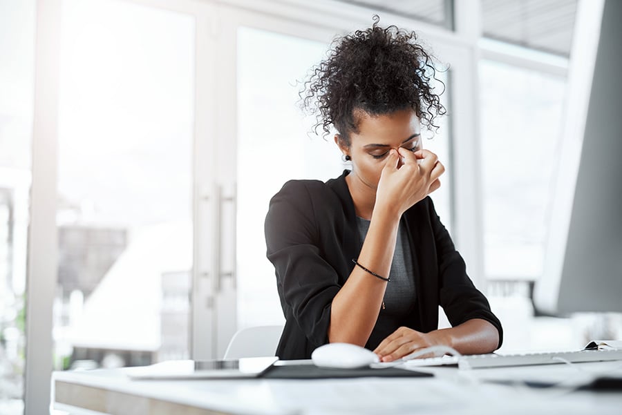 A stressed woman rubbing her eyes in an office