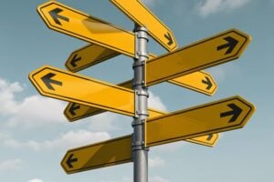 A metal pole with numerous blank yellow signposts pointing in multiple directions