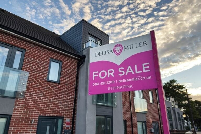 Bright pink for sale sign on brick homes in Manchester