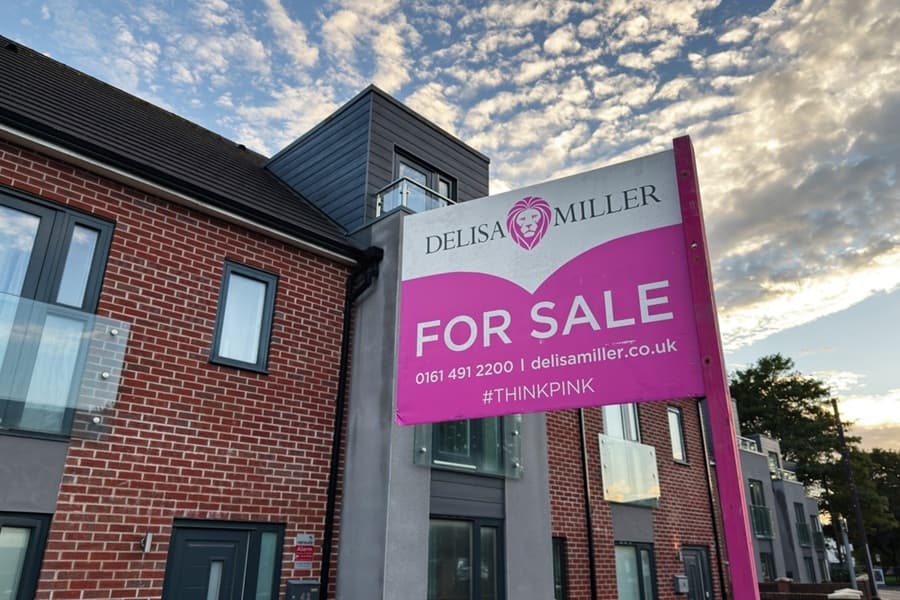 Bright pink for sale sign on brick homes in Manchester