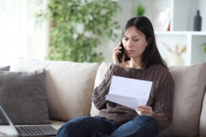 An angry looking woman making a phone call while holding a letter
