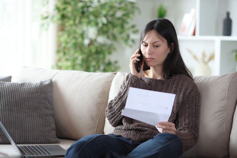 An angry looking woman making a phone call while holding a letter