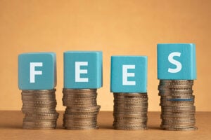 The word 'fees' spelled out in blue blocks on top of piles of coins