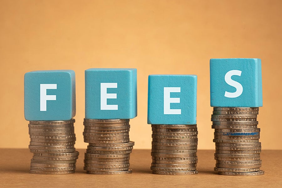 The word 'fees' spelled out in blue blocks on top of piles of coins